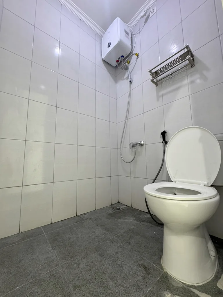 Kamar mandi dengan kloset duduk, shower, dan water heater