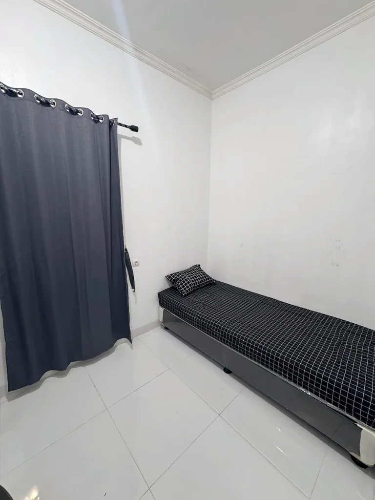 Tempat tidur single dengan seprai hitam bermotif kotak dan tirai gelap